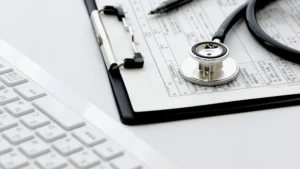 Medical clipboard, stethoscope and keyboard on a desk representing CPT 96127 behavioral assessment billing