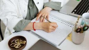Clinician making notes at a desk with a laptop, representing DEA telehealth controlled substance prescribing rules for psychiatry