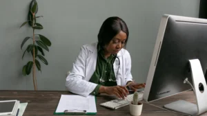 Clinician reviewing a patient history form at a desk computer, representing ICD-10 code F43.10 PTSD documentation