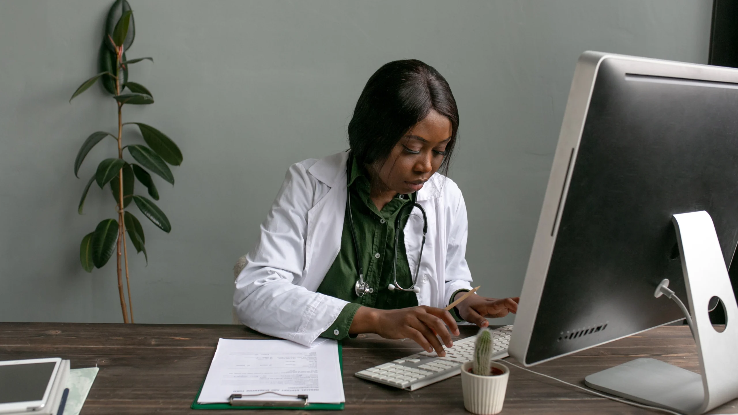 Clinician reviewing a patient history form at a desk computer, representing ICD-10 code F43.10 PTSD documentation