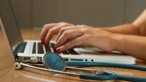 Clinician entering diagnosis codes on a laptop beside a stethoscope, representing ICD-10 code Z87.893 documentation